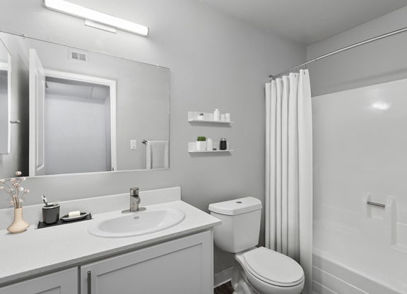 Model Bathroom with White Cabinets and Wood-Style Flooring at The Archer Apartments in Sacramento, CA.