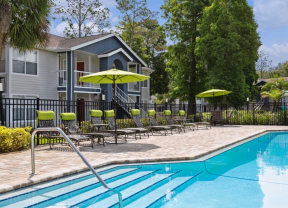 Swimming pool with chaise lounge chairs and umbrellas in front of a house