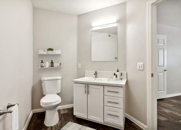 Model Bathroom with Wood-Style Flooring and White Cabinets at Loma Vista Apartments in Las Vegas, NV.