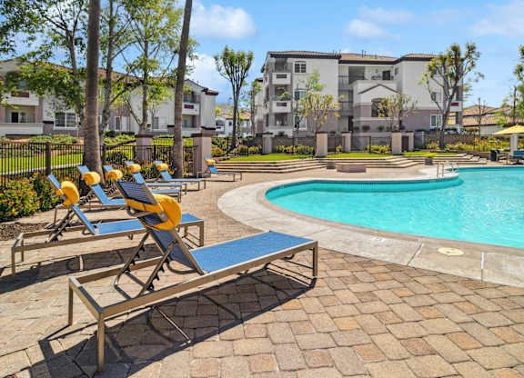 A poolside area with sun loungers and a bench.