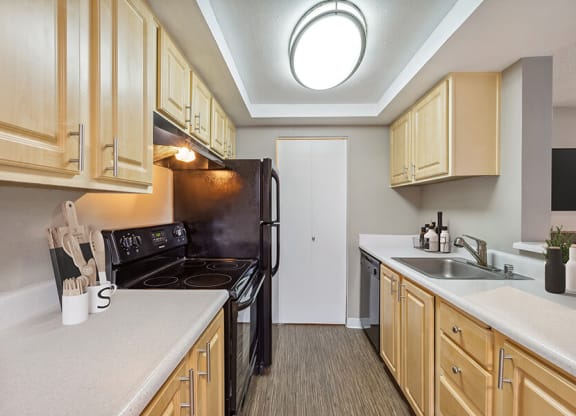 Model Kitchen with Dark Wood Cabinets and Wood-Style Flooring at Grammercy Apartments located in Renton, WA.