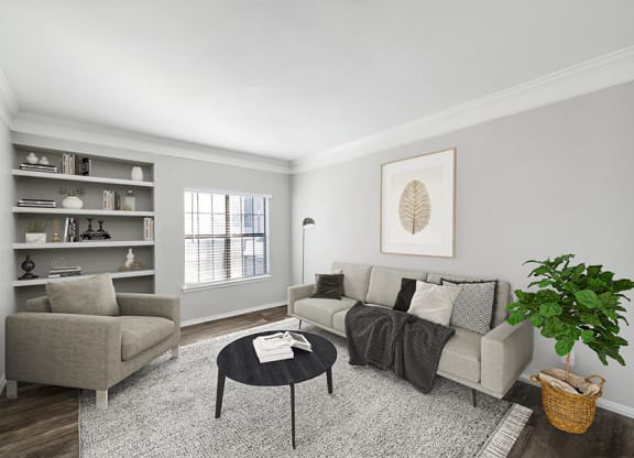 Three-Bedroom Apartments in Lewisville, TX - Bridges at Oakbend - Cozy Living Room With Plush Sofa And Chair, Built-In Shelving, Round Coffee Table, And Window With Blinds.