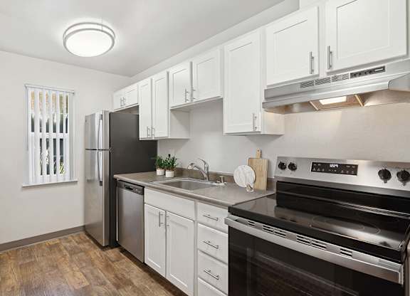 Model Kitchen with White Cabinets and Wood-Style Flooring at Los Gatos Landing Apartments located in San Jose, CA.