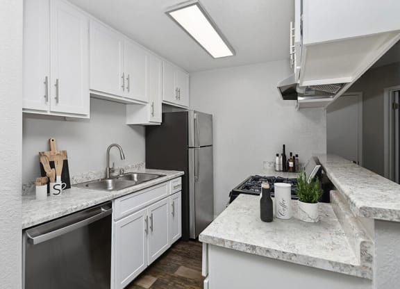 Model Kitchen with White Cabinets and Wood-Style Flooring at The Meritage Apartments in Vallejo, CA.