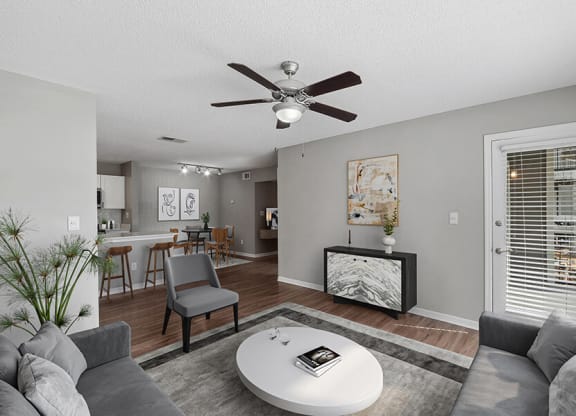 Model Living Room with Wood-Style Flooring and View of Kitchen/Dining Area at Fountains Lee Vista Apartments in Orlando, FL.