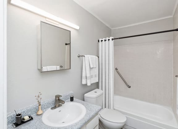 Model Bathroom with White Cabinets, Wood-Style Flooring and Shower/Tub at Indigo Park Apartments located in Albuquerque, NM.