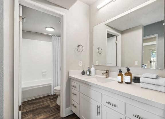 Model Bathroom 2 with Bathtub/Shower, Wood-Style Flooring & White Cabinets at Forest Park Apartments in El Cajon, CA.