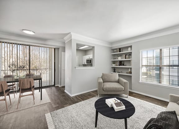 Model Living Room and Dining Room with Wood-Style Flooring and Patio Accessibility at Bridges at Oakbend Apartments located in Lewisville, TX.