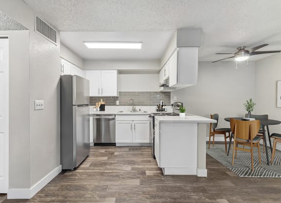 Model Kitchen with White Cabinets and Wood-Style Flooring with view of Dining Room at Meadow Ridge Apartments in Las Vegas, NV.