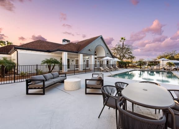 a swimming pool with tables and chairs next to a building