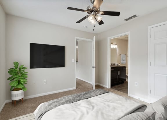 Model bedroom with ceiling fan and attached bath