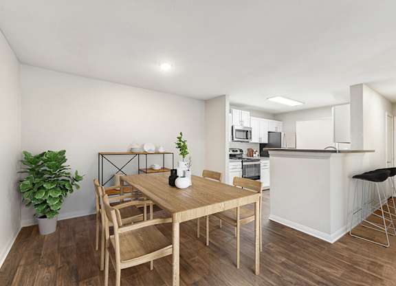 Model Dining Room with Wood-Style Flooring and View of Kitchen at Lake Cameron Apartments located in Apex, NC.