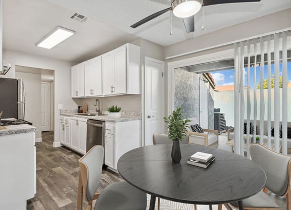Model Dining Room with Wood-Style Flooring, View of Kitchen and Patio Accessibility at Peaks on 4th Apartments in Avondale, AZ.