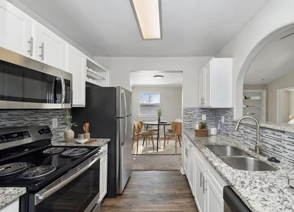 Model Kitchen with White Cabinets and Wood-Style Flooring at Hidden Creek Apartments in Lewisville, TX.