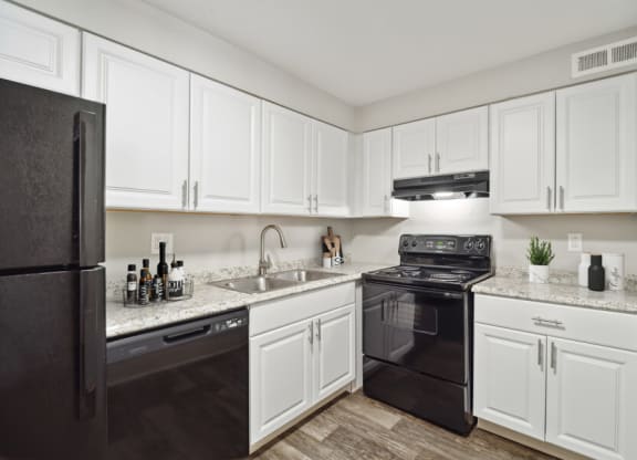 a kitchen with white cabinets and black appliances