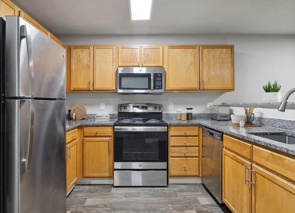 Model Kitchen with Wood-Style Flooring and Oak Cabinets at Retreat at Stonecrest Apartments located in Lithonia, GA.