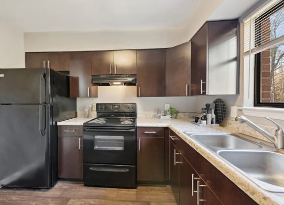 Model Kitchen with Brown Cabinets and Tile Flooring at Spring Forest Apartments in Raleigh, NC.