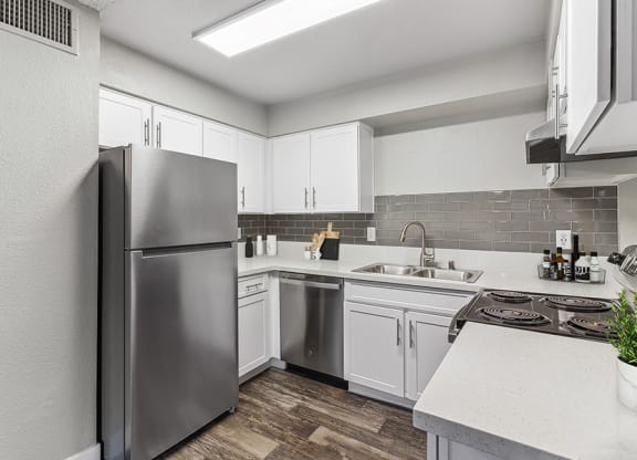 Model Kitchen with White Cabinets and Wood-Style Flooring at Meadow Ridge Apartments in Las Vegas, NV.