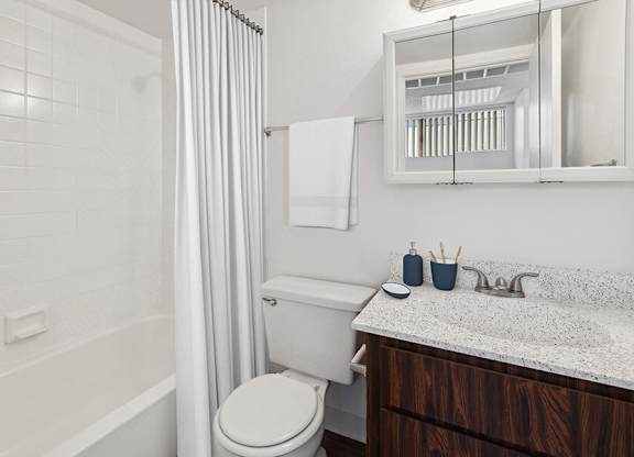 Model Bathroom with Dark Wood Cabinets, Wood-Style Flooring and Shower/Tub at Lakeside Casitas Apartments located in Tucson, AZ.