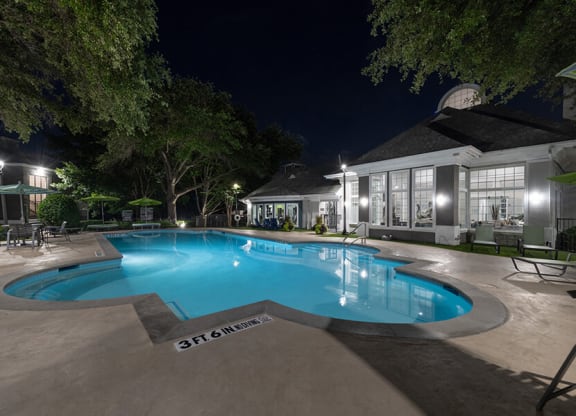 Community Swimming Pool with Pool Furniture at Bridges at Oakbend Apartments located in Lewisville, TX.