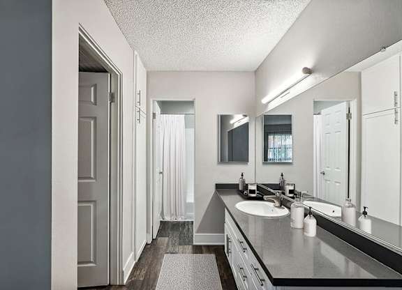 Model Bathroom with White Cabinets and Wood-Style Flooring at Madison Park Apartments located in Anaheim, CA.