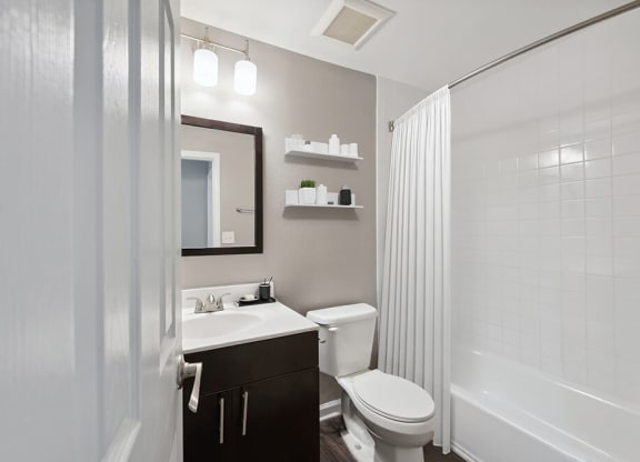 Model Bathroom with Dark Cabinets, Wood-Style Flooring and Shower/Tub at Spring Forest Apartments in Raleigh, NC.