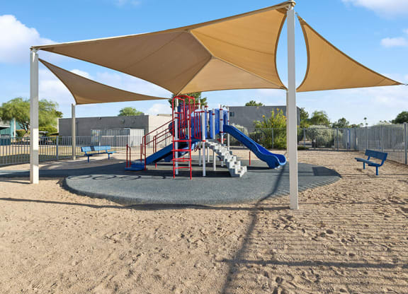Community Playground with Slide and Tan Canopy at Tanque Verde Apartments located in Tucson, AZ.