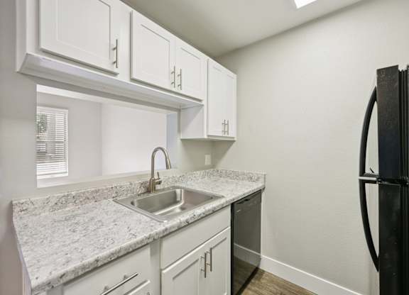 Model kitchen with white cabinets and a black refrigerator.