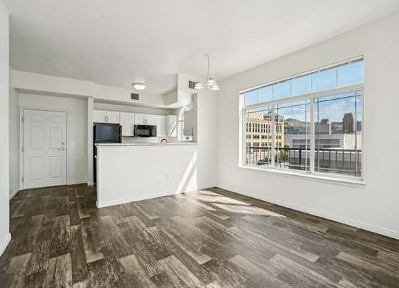 Model Kitchen with Wood-Style Flooring, White Cabinets, and Black Appliances at Altitude on Fifth Apartments located in Salt Lake City, UT.
