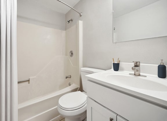 Model Bathroom with White Cabinets, Tile Flooring and Shower/Tub at Middlesex Crossing Apartments in Billerica, MA.