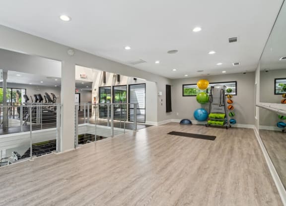 Community Fitness Center with Yoga Area and Wall Mirrors at Dunwoody Village Apartments in Atlanta, GA.