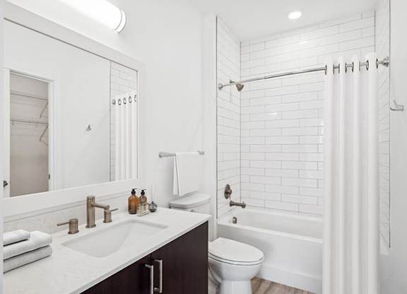 Model Bathroom with Dark Cabinets, Wood-Style Flooring and Shower/Tub at Stella Apartments located in New Carrollton, MD.