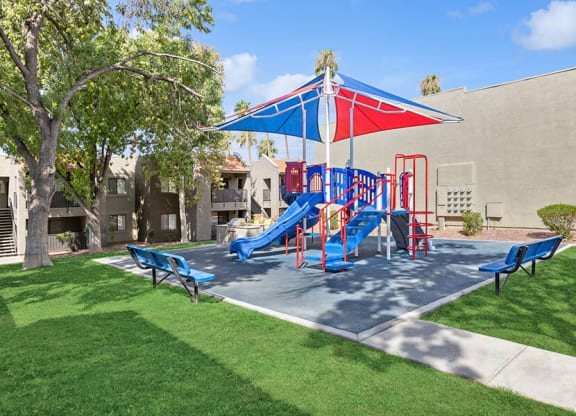 Community Playground with a Slide and Blue/Red Canopy at Saddle Ridge Apartments in Tucson, AZ.