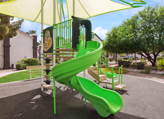 Community Playground with a Slide and Green Canopy at Meadow Ridge Apartments in Las Vegas, NV.