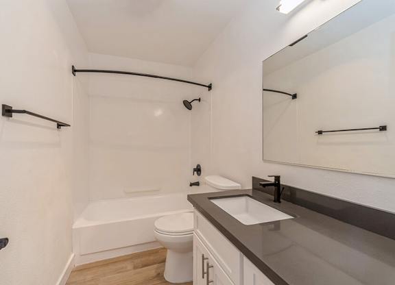 Model Bathroom with White Cabinets and Wood-Style Flooring at Palmilla Apartments located in San Diego, CA.