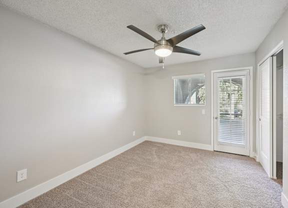 A room with a ceiling fan and carpeted floor.