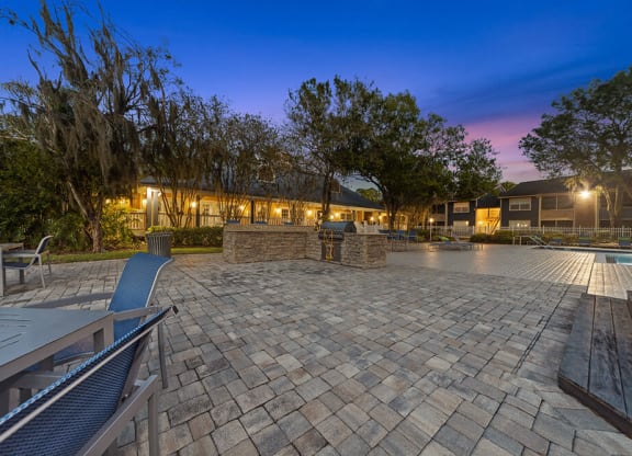 Outdoor BBQ Area with Furniture and Pool View at Walden Lake Apartments in Plant City, FL.