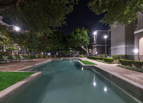 Community Swimming Pool with Pool Furniture at Bridges at Oakbend Apartments located in Lewisville, TX.
