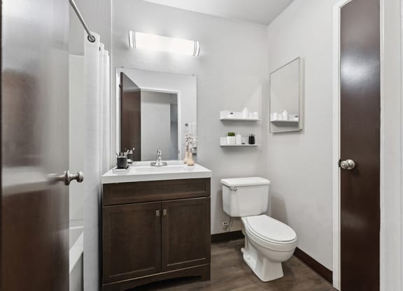 Model Bathroom with Dark Wood Cabinets and Wood-Style Flooring at Creek at 2645 Apartments located in Sacramento, CA.