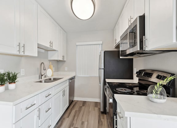 Model Kitchen with White Cabinets and Wood-Style Flooring at Bridges on Sunset Apartments in Suisun City, CA.