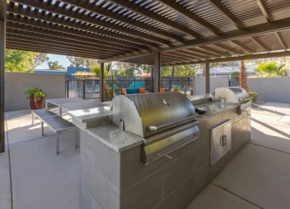 An outdoor kitchen with a grill and a pergola  at Lakeside Casitas in Tucson, AZ