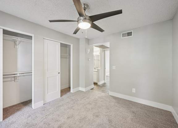 Model living room with a ceiling fan and carpeted floor.