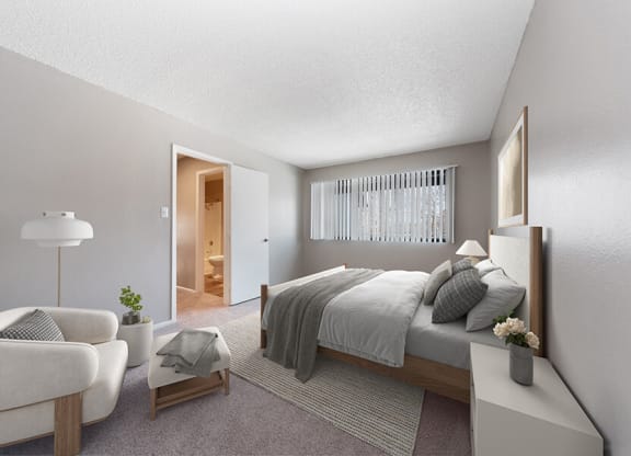Pet-Friendly Affordable Apartments in South Denver, CO - Bridges at 9 Mile Station - A Bedroom With Neutral Bedding, Cozy Accent Chair, Soft Carpet, And Wide Window Blinds.