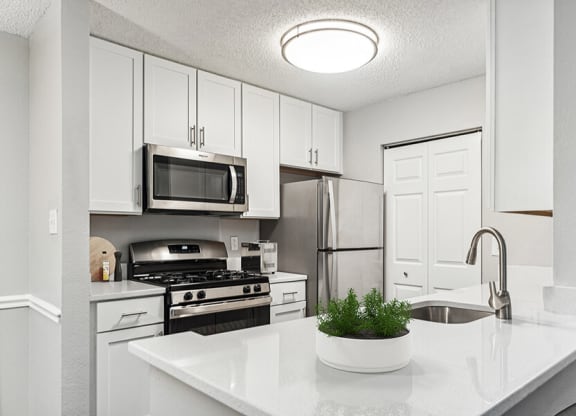 Model Kitchen with White Cabinets and Wood-Style Flooring at Commons at Haynes Farm Apartments in Shrewsbury, MA.