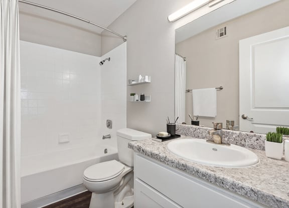 Model Bathroom with White Cabinets, Wood-Style Flooring and Shower/Tub at Peaks on 4th Apartments in Avondale, AZ.