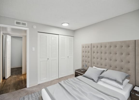 a bedroom with white walls and a white bed with gray pillows