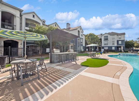 Community Swimming Pool with Pool Furniture at Park West Apartments located in Houston, TX.