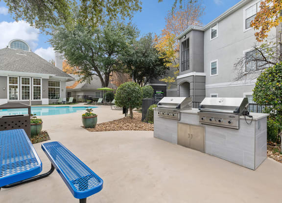 Outdoor BBQ Area with Furniture and Pool View at Bridges at Oakbend Apartments in Lewisville, TX.