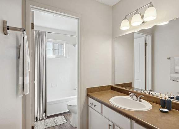 Model Bathroom with White Cabinets, Wood-Style Flooring and Shower/Tub at Los Gatos Landing Apartments located in San Jose, CA.
