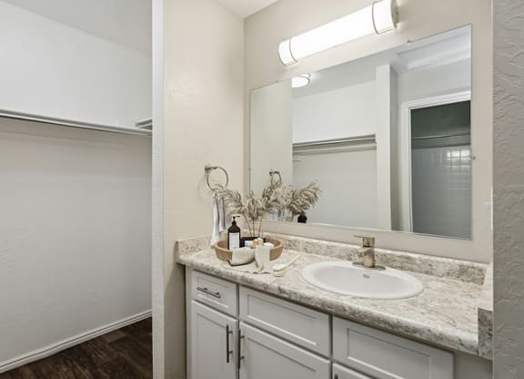 Model Bathroom with White Cabinets, Wood-Style Flooring & Closet at Broadmoor Village Apartments in Salt Lake City, UT.